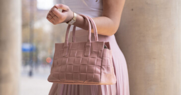 Eine rosafarbene Damen Handtasche mit einem geflochtenen Design in der Stadt.