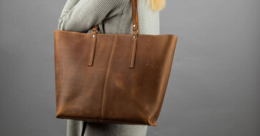Eine große braune Damen Reisetasche aus Leder, getragen von einem elegantin Mann.