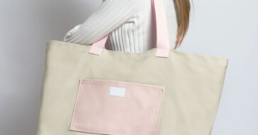 Eine beige Damen Shoppertasche mit rosa Details, getragen von einer Frau.