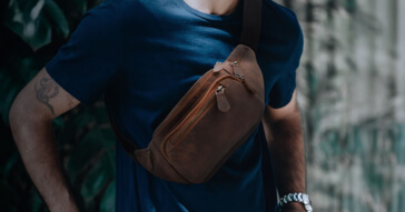 Ein Mann trägt eine stilvolle braune Herren-Gürteltasche aus Leder über der Schulter.